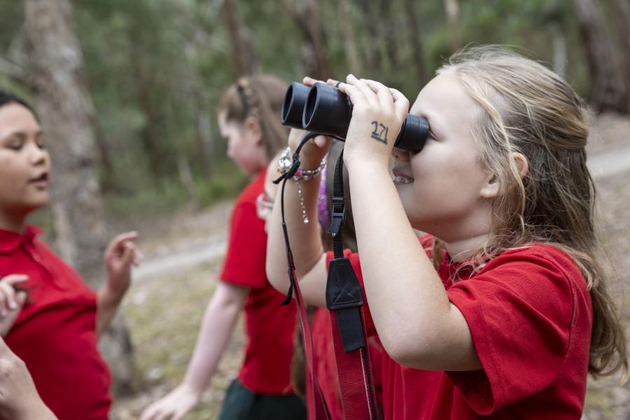 Primary school student using binoculars