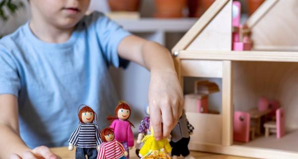 Young child playing with doll family and doll house