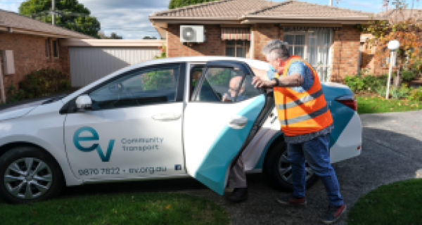 Person in high vis vest assists someone out of an eastern volunteers branded car