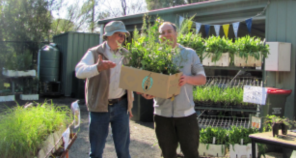 Two men pose with seedlings