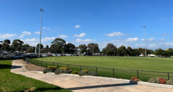 sports oval surrounded by black chain link fence with trees on the horizon and a clear blue sky