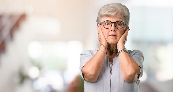 Older woman with hands over ears due to noise