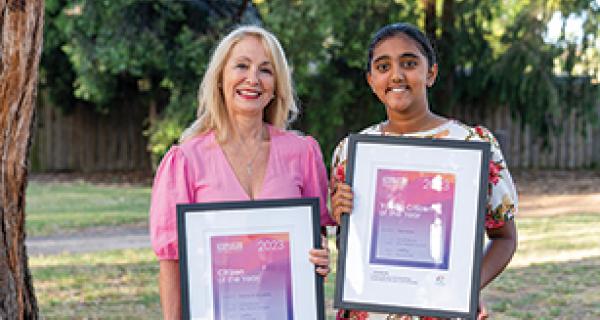 Photo of two females holding awards