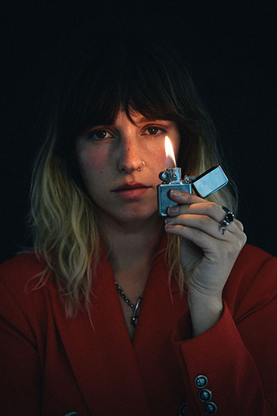 Close up of the female artist in a dark room with a small lighter held to her face
