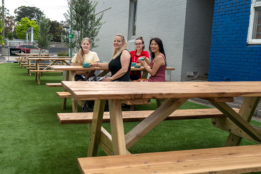 4 women sitting at tables at the Urban Picnic Park in Blackburn Village