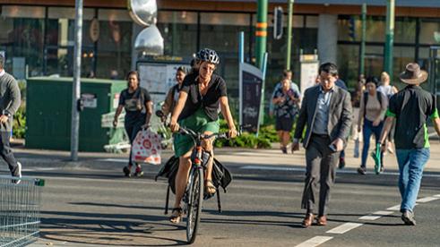 A person riding a bike across a road and pedestrians crossing a road