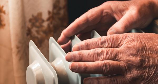 Older person warming hands over a heater