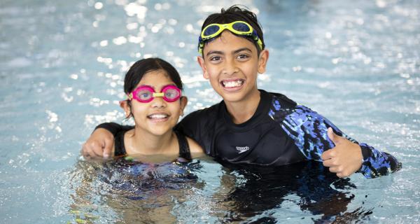 Kids in the pool, smiling at the camera 
