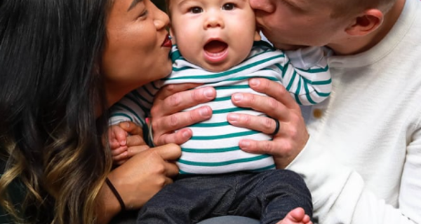 Parents on either side of baby, giving kisses on babies cheek