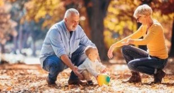 grandparents playing outdoor with a toddler in Autumn