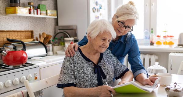 Two older ladies reading at kitchen bench 