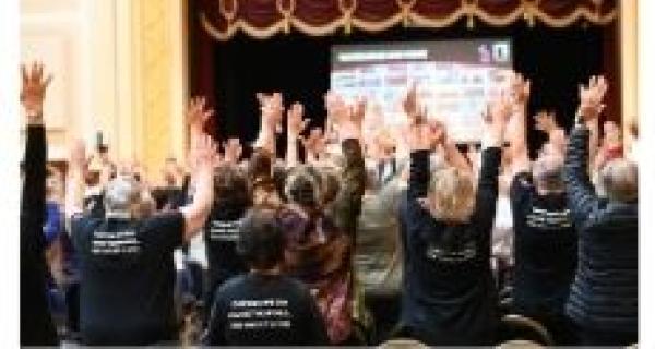 people singing wearing black tshirts at townhall