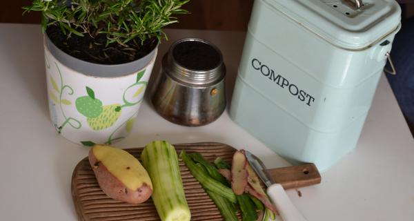 a photo of veggie scraps with compost caddy in the background