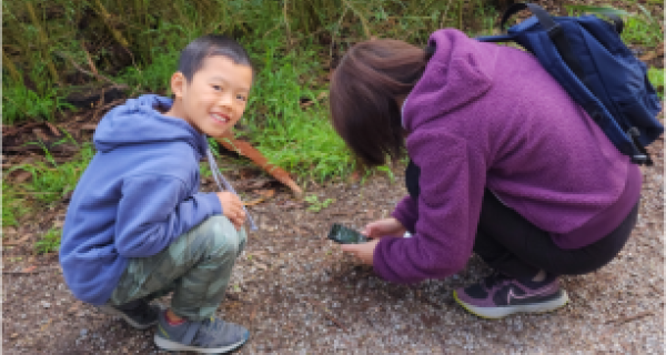 Mother and son outside using their phones to take pictures of flora and fauna