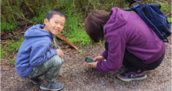 Mother and son outside using their phones to take pictures of flora and fauna 