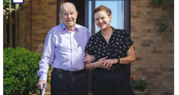 Older man with walking stick linked arm with women 