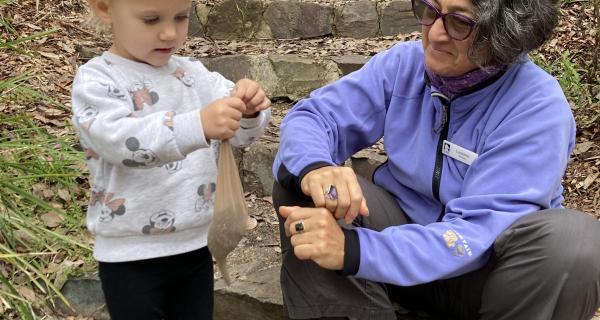 Preschool age girl with volunteer making a craft in the bush.