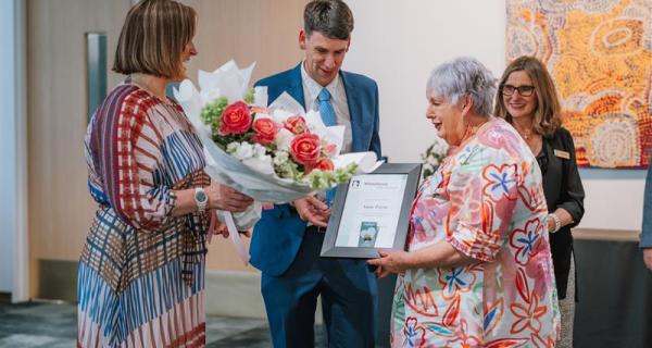 a group of people presenting flowers and a framed certificate to a volunteer
