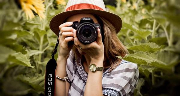 Young person looking through camera lense, taking a photo