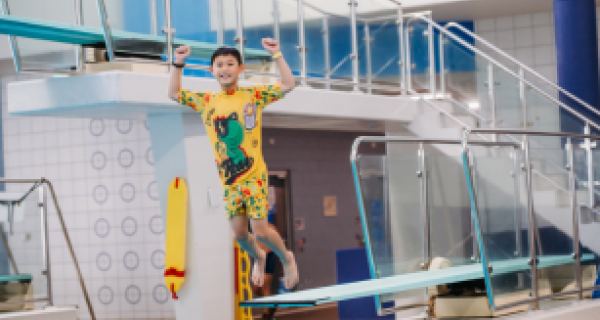 A boy jumps off a dive board.