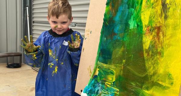 little boy painting with her hands 