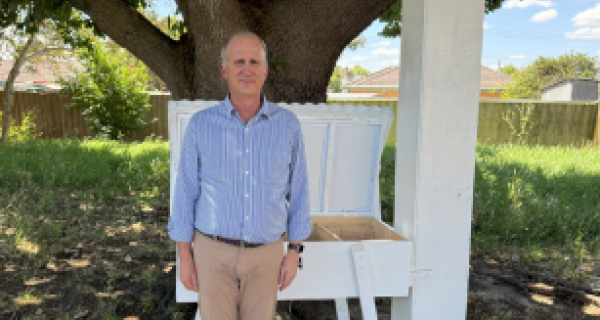 Michael stands next to his beehive