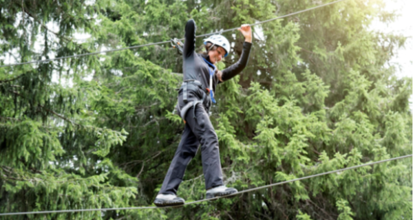 Young girl walking along a tightrope course, high up in the tree tops