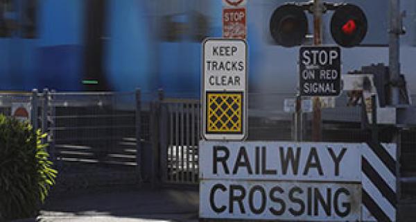 Railway crossing with gates down and lights on with training passing through