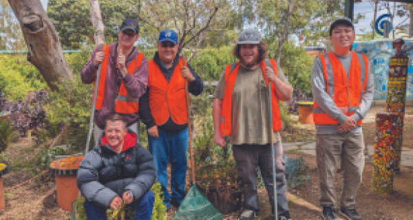 five male volunteers in orange vests pose for the camera