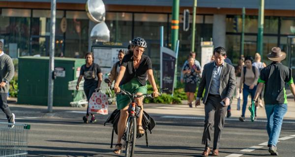 People riding bikes and walking across a busy intersection