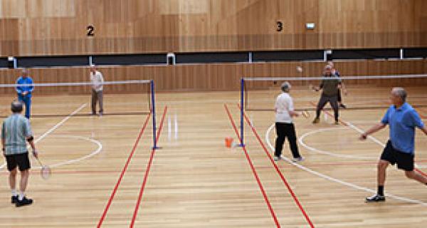people playing badminton on 2 indoor courts