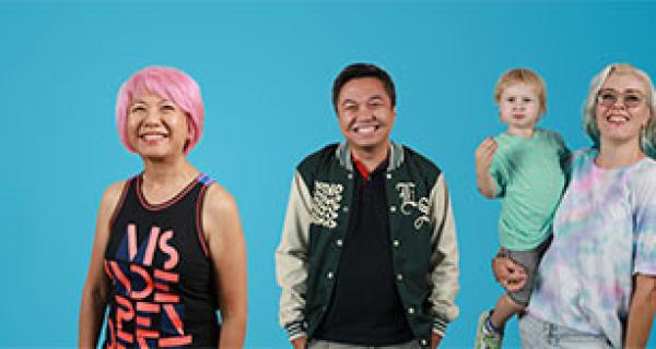 3 people standing and smiling. A lady is holding a young child