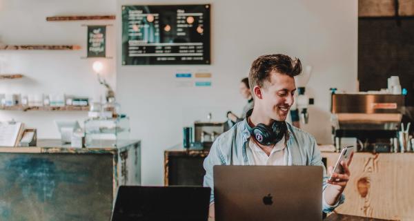 Man in cafe on laptop and phone