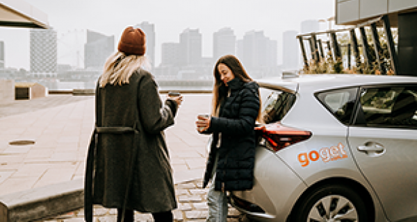 Women drinking coffee next to car