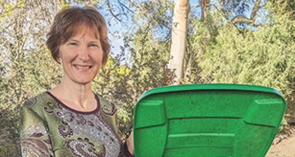 Woman displays food and garden organics bin with garden waste inside