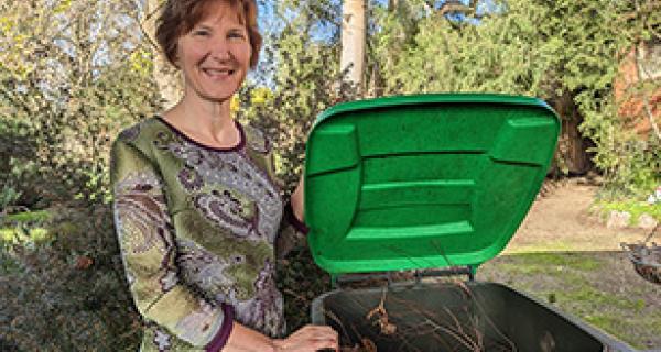 Woman lifts green lid to show contents of food and organics bin