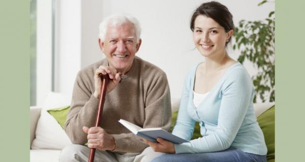 Older man and support worker smiling with book