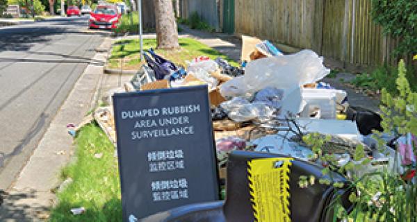 Pile of dumped rubbish with a 'dumped rubbish under surveillance' sign 