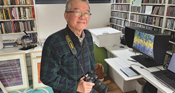 Photographer in studio walled with books and an artistic image on a screen