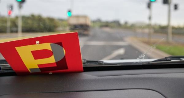 Learner and P Plates on a car dashboard with a road and countryside in the distance