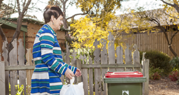 Woman is walking trash to her outdoor bin