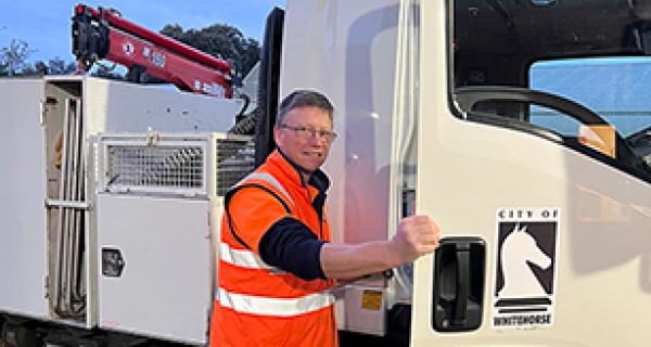 Man in orange high-vis vest climbing into truck 