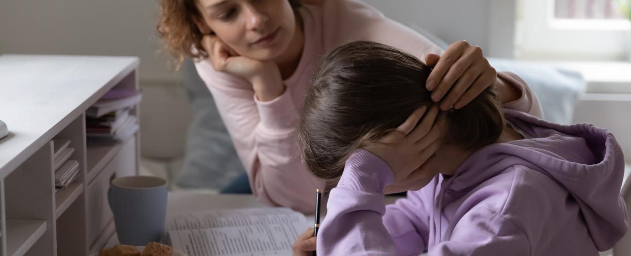 Mother comforting her young daughter doing her school work