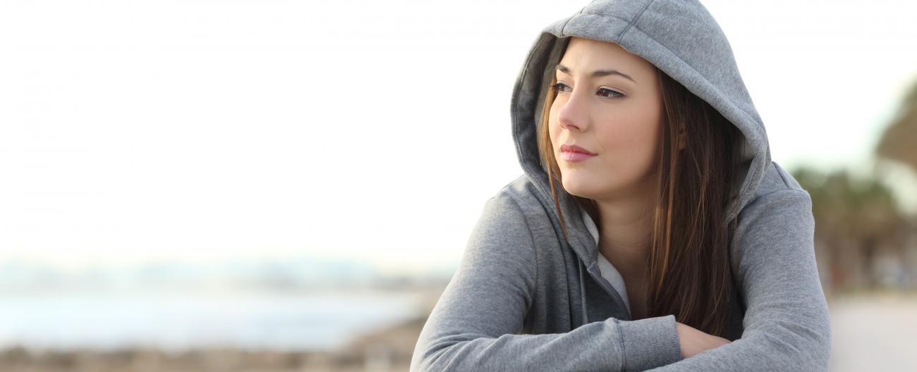 Young girl sitting on the beach pondering