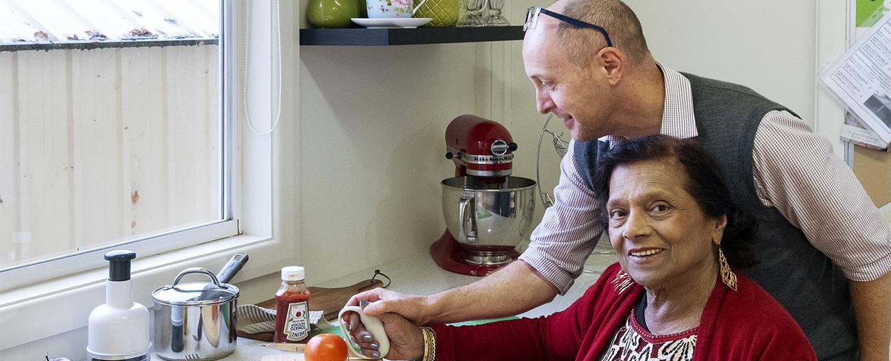 Occupational therapist assisting older woman with kitchen aids