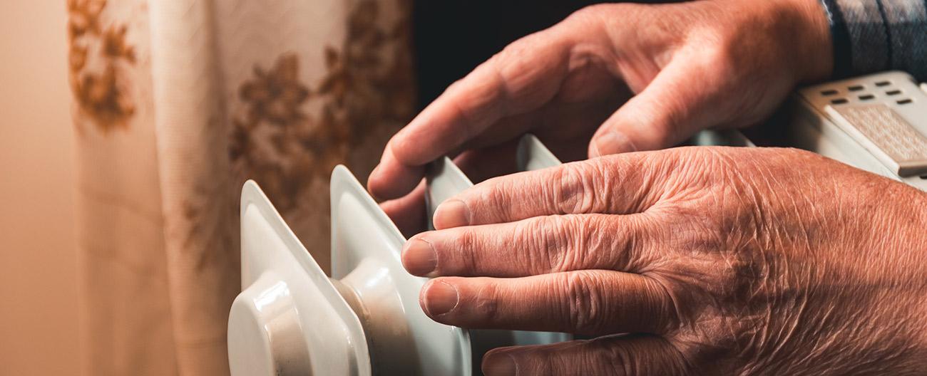 Older person warming hands over a heater