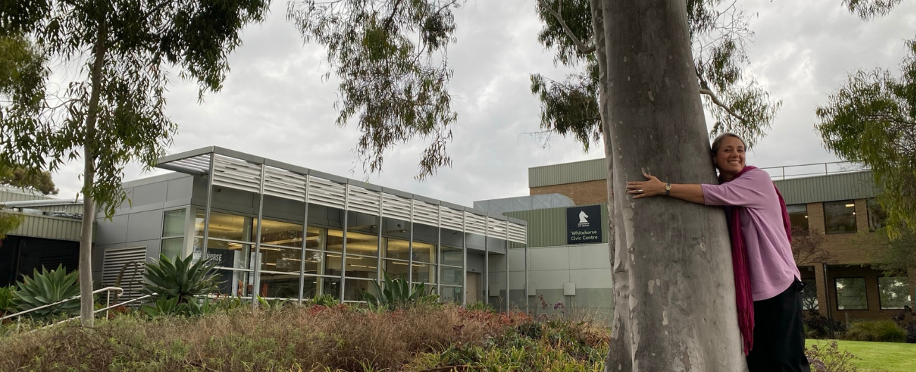 Woman hugs lemon scented gum tree outside Civic Centre