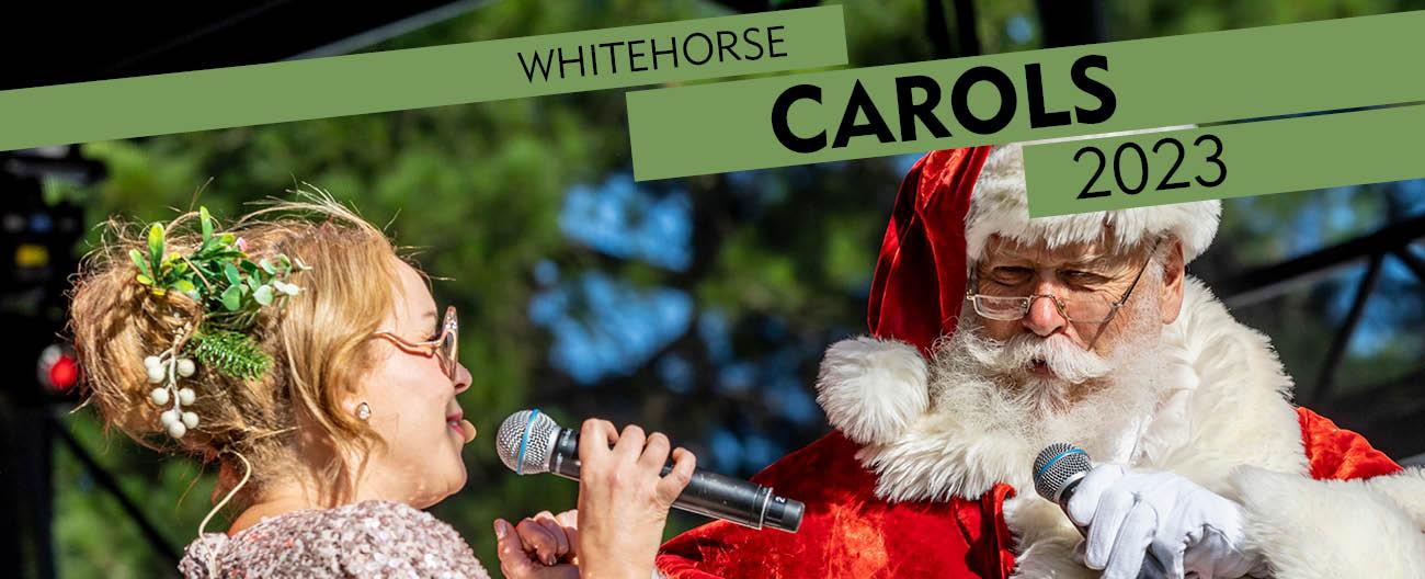 Santa singing into a microphone to a blonde women to his left