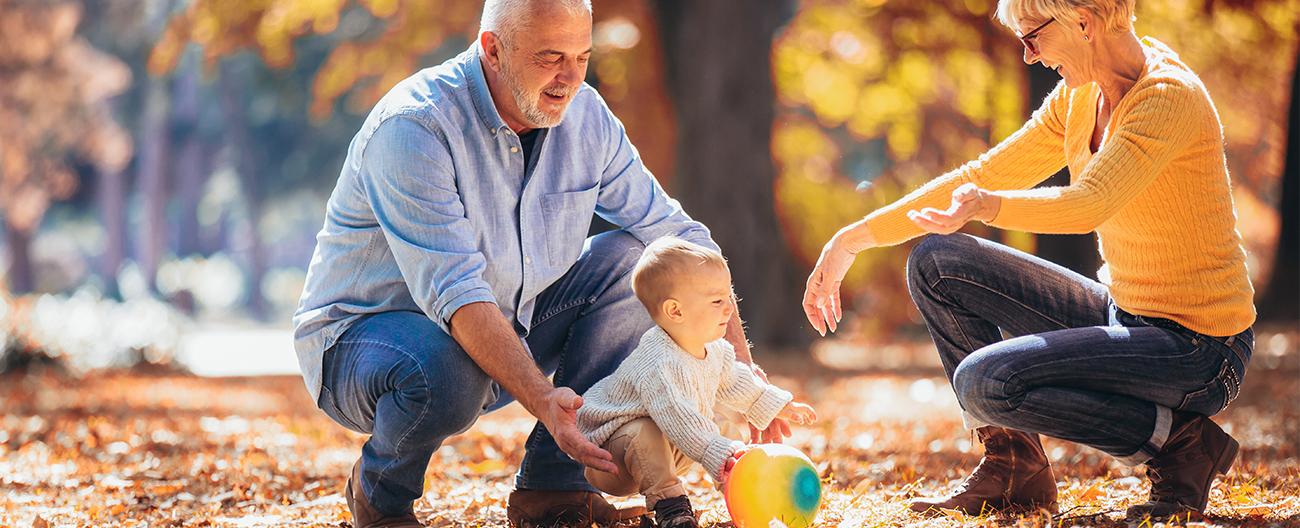 grandparents playing outdoor with a toddler in Autumn