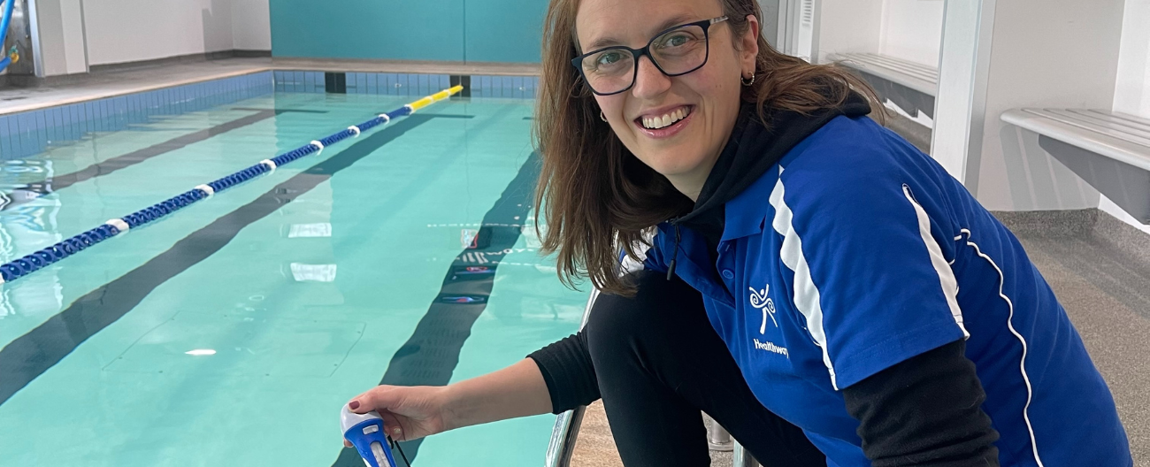 Theresa from Healthways next to the pool holding a thermometer. 